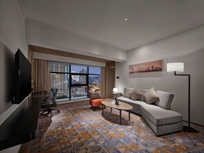 A modern hotel room with a large window offering a city view, a sofa, a coffee table, and a flat-screen TV. - Hilton Garden Inn Guangzhou Tianhe (Guangzhou)