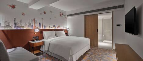 Una habitación de hotel moderna con una cama bien tendida, un escritorio con silla, un televisor de pantalla plana y una zona de ducha.