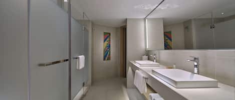 A modern bathroom with a glass shower enclosure, a large mirror, and a white sink with a towel rack.