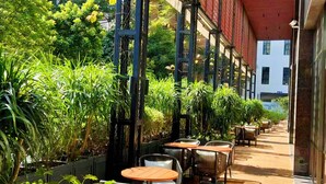 An outdoor patio area with tables and chairs, surrounded by lush greenery and a red ceiling. - Hilton Garden Inn Guangzhou Tianhe (Guangzhou)