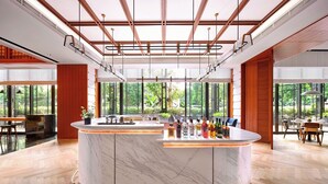A modern bar area with a marble countertop, multiple liquor bottles, and a view of greenery outside. - Hilton Garden Inn Guangzhou Tianhe (Guangzhou)