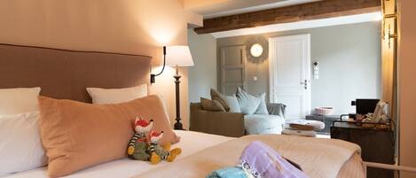 A hotel room with a bed, pillows, a stuffed toy, and a folded towel.