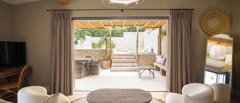 Un salón amplio con una televisión grande, asientos cómodos y vistas a un patio exterior.