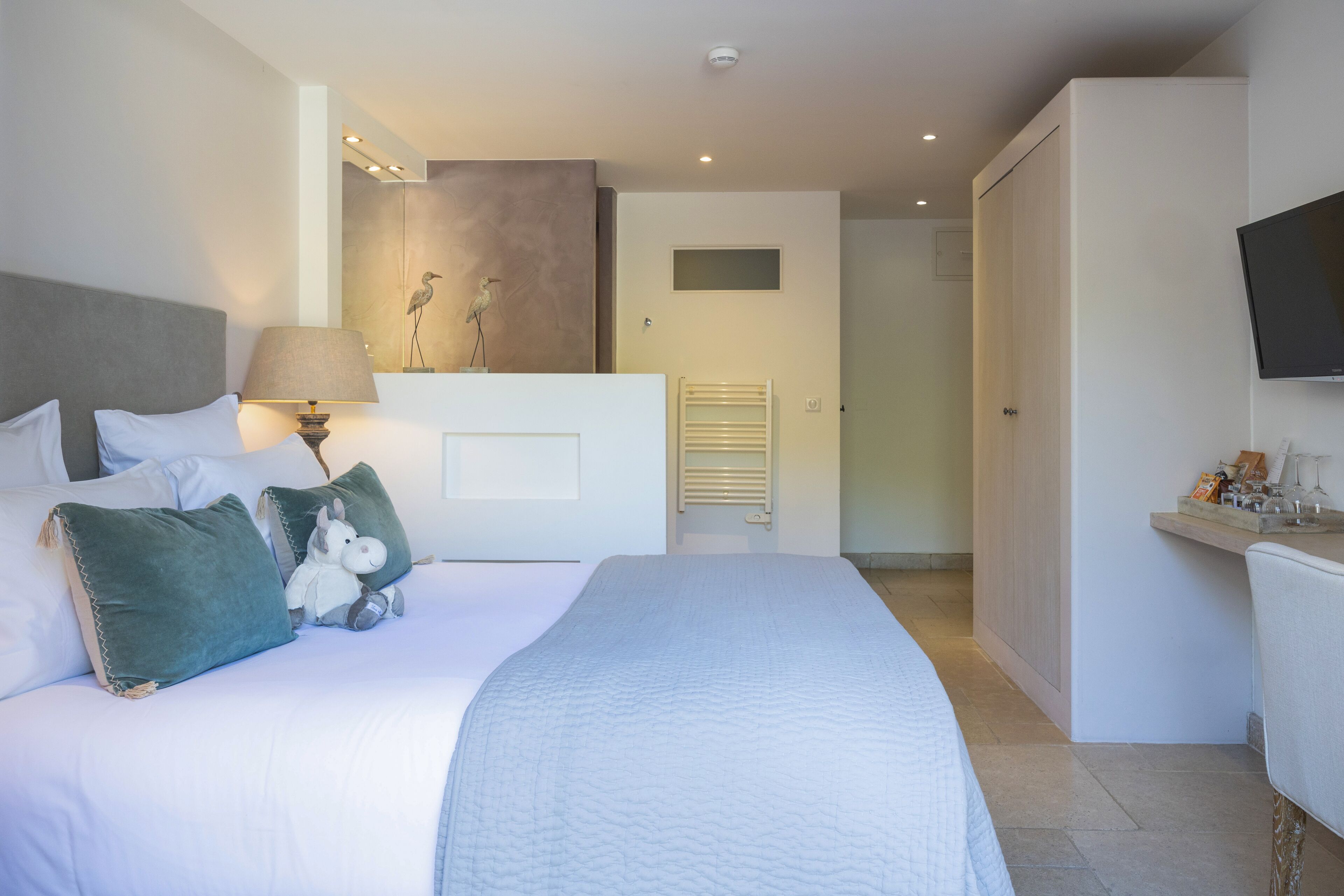 Een moderne hotelkamer met een groot bed, een bedlampje, een flatscreen televisie en een klein tafeltje met een dienblad.