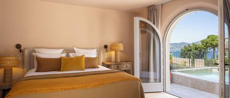 Un dormitorio con una cama grande, una mesita de noche, una lámpara y vistas a una piscina a través de una puerta abierta.