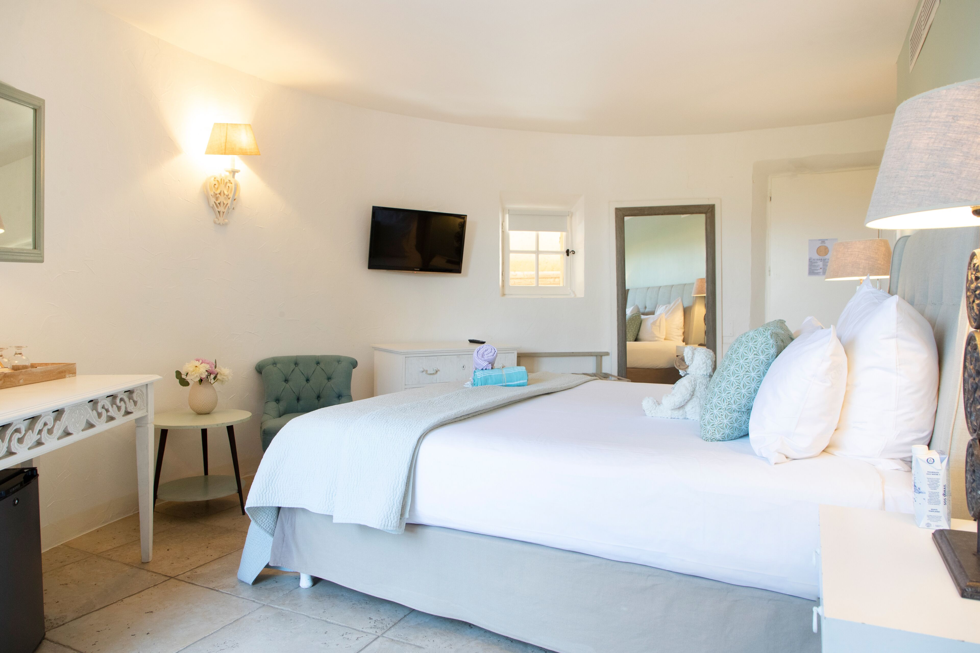 A hotel room with a bed, a desk, a chair, a TV, and a window.