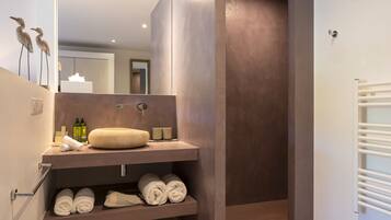 Une salle de bain moderne avec un grand miroir, un lavabo beige et un porte-serviettes.