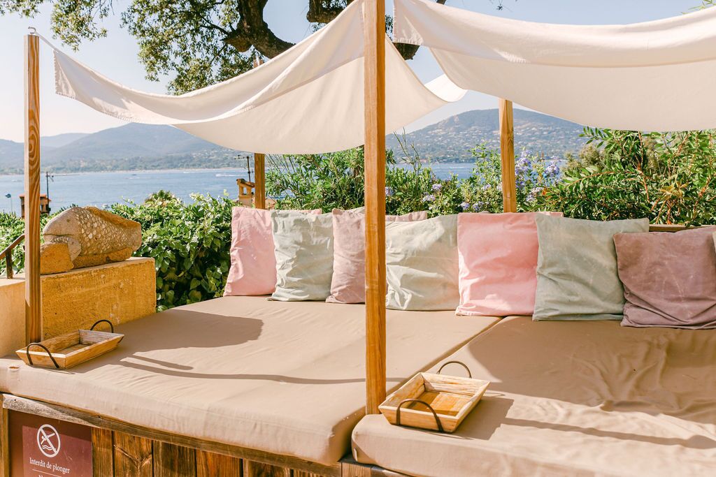 A cozy outdoor seating area with a cushioned bench, a wooden tray, and a stone sculpture.