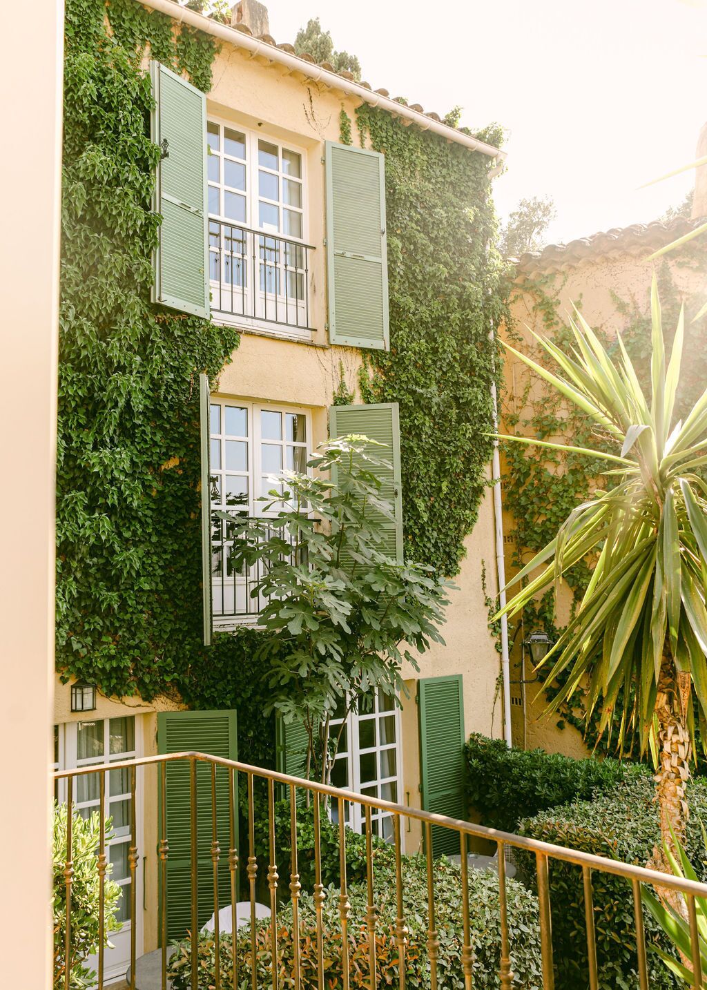 Un immeuble avec des volets verts, un balcon et un escalier.
