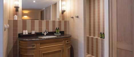 Un baño moderno con tocador de madera, un espejo grande y zona de ducha.