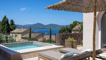 Zona de piscina con sillas de descanso y una pérgola con vistas panorámicas.