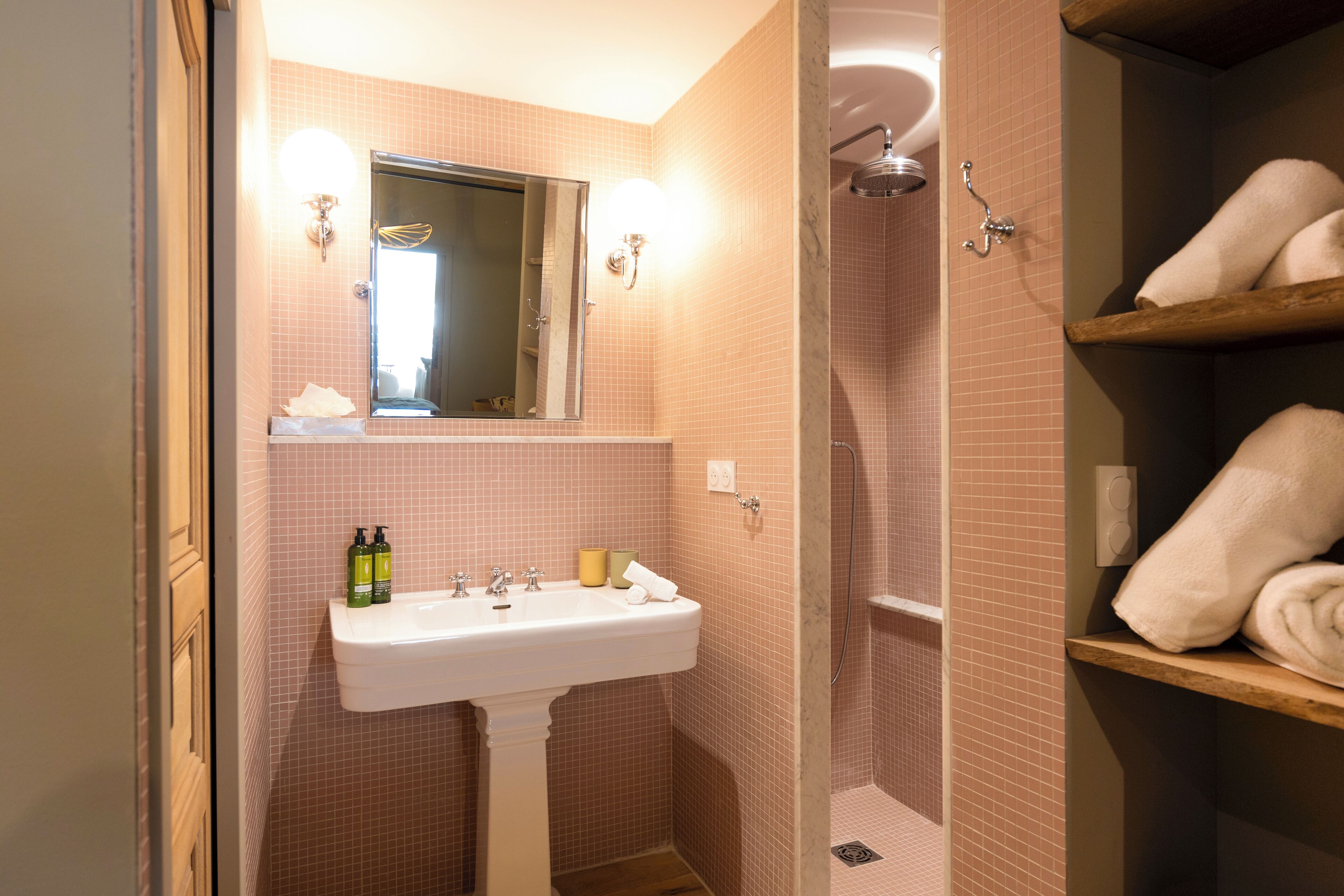 A bathroom with a sink, mirror, and shower.