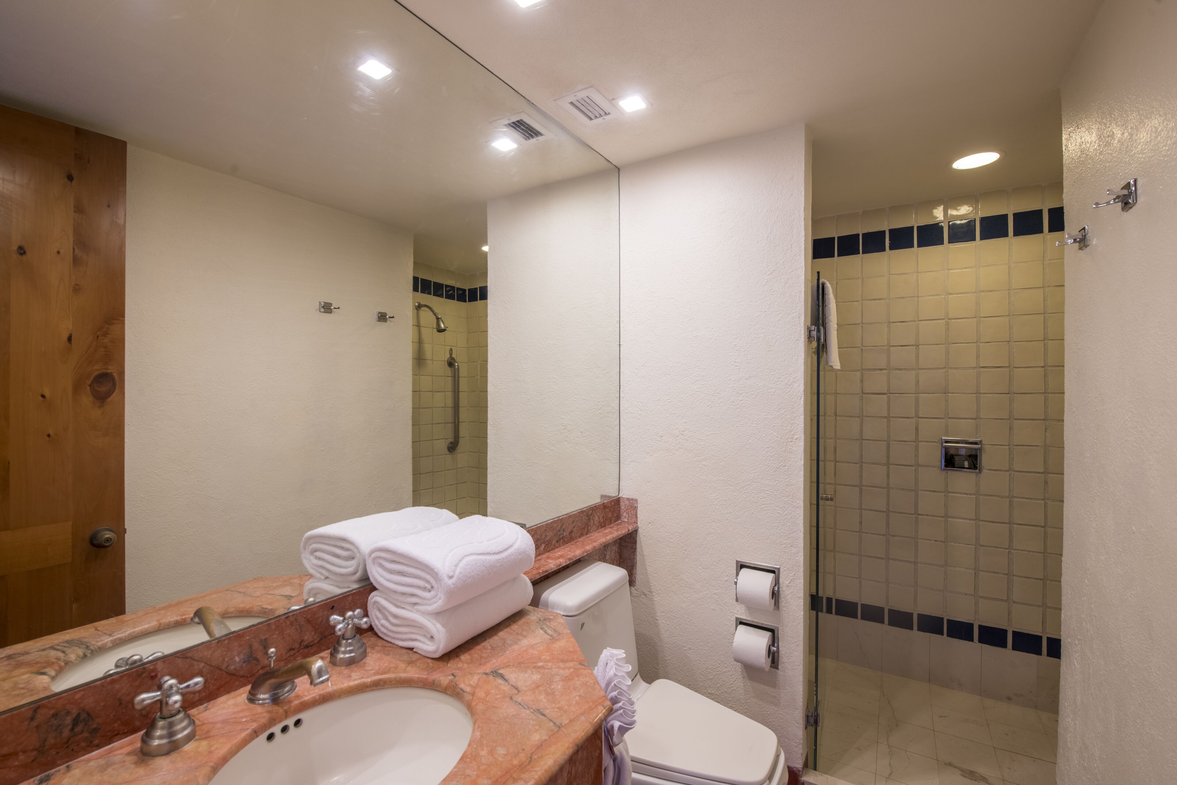 A bathroom with a marble sink, a toilet, a shower, and a mirror.
