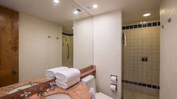 Une salle de bain avec un lavabo en marbre, des toilettes, une douche et un miroir.