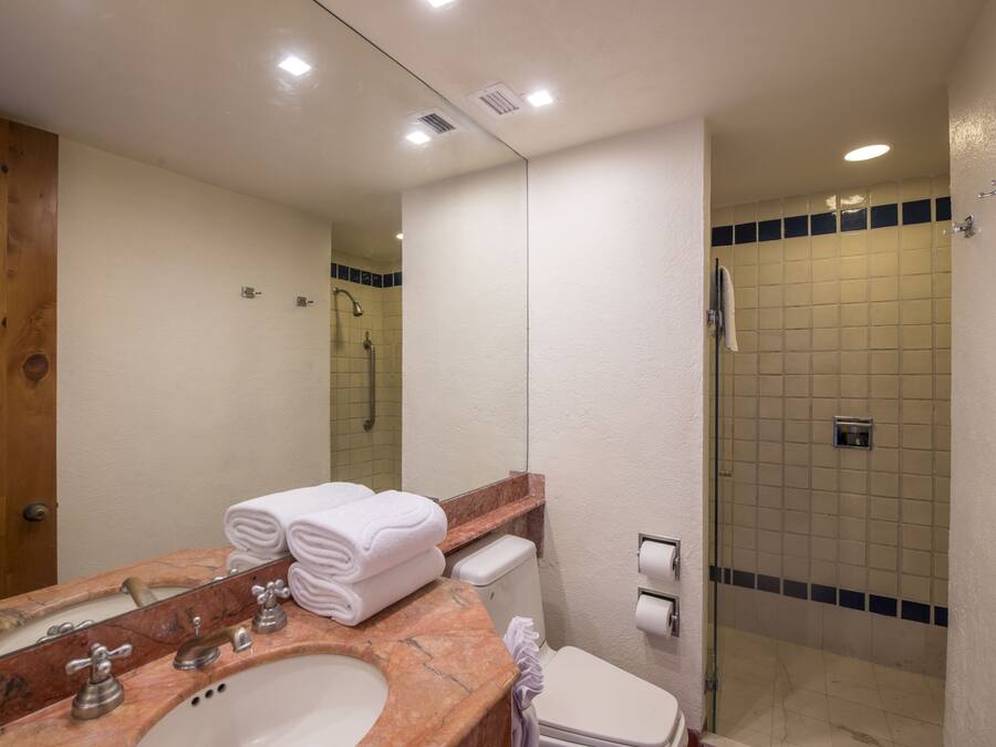 Une salle de bain avec un lavabo en marbre, des toilettes, une douche et un miroir.