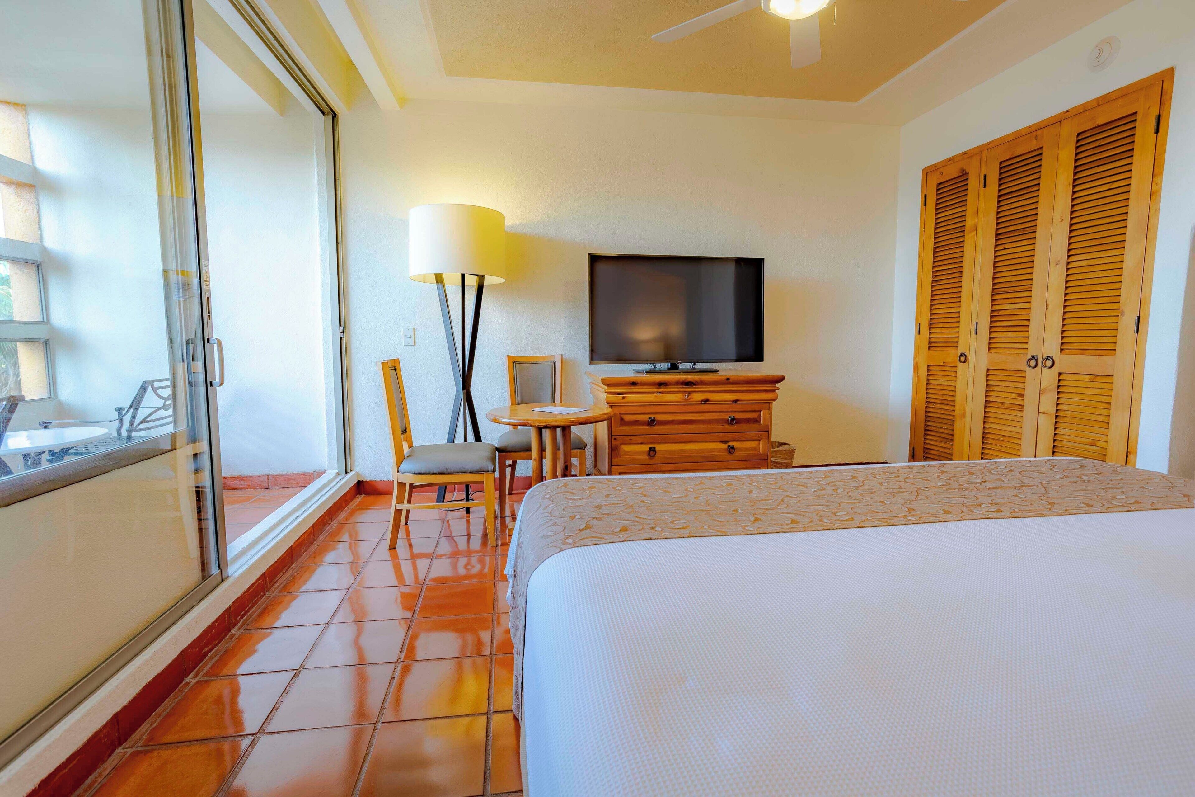 Een hotelkamer met een bed, een televisie, een bureau met stoel, en een kledingkast.