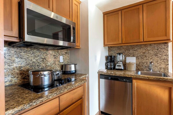 A kitchen with granite countertops, stainless steel appliances, and wooden cabinets.
