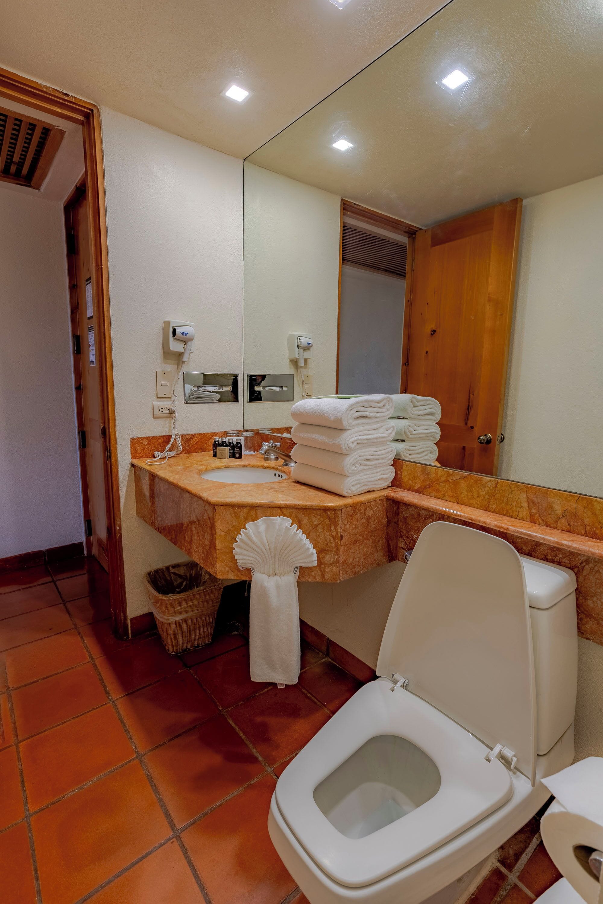 A bathroom with a toilet, a sink, a mirror, and a towel rack.