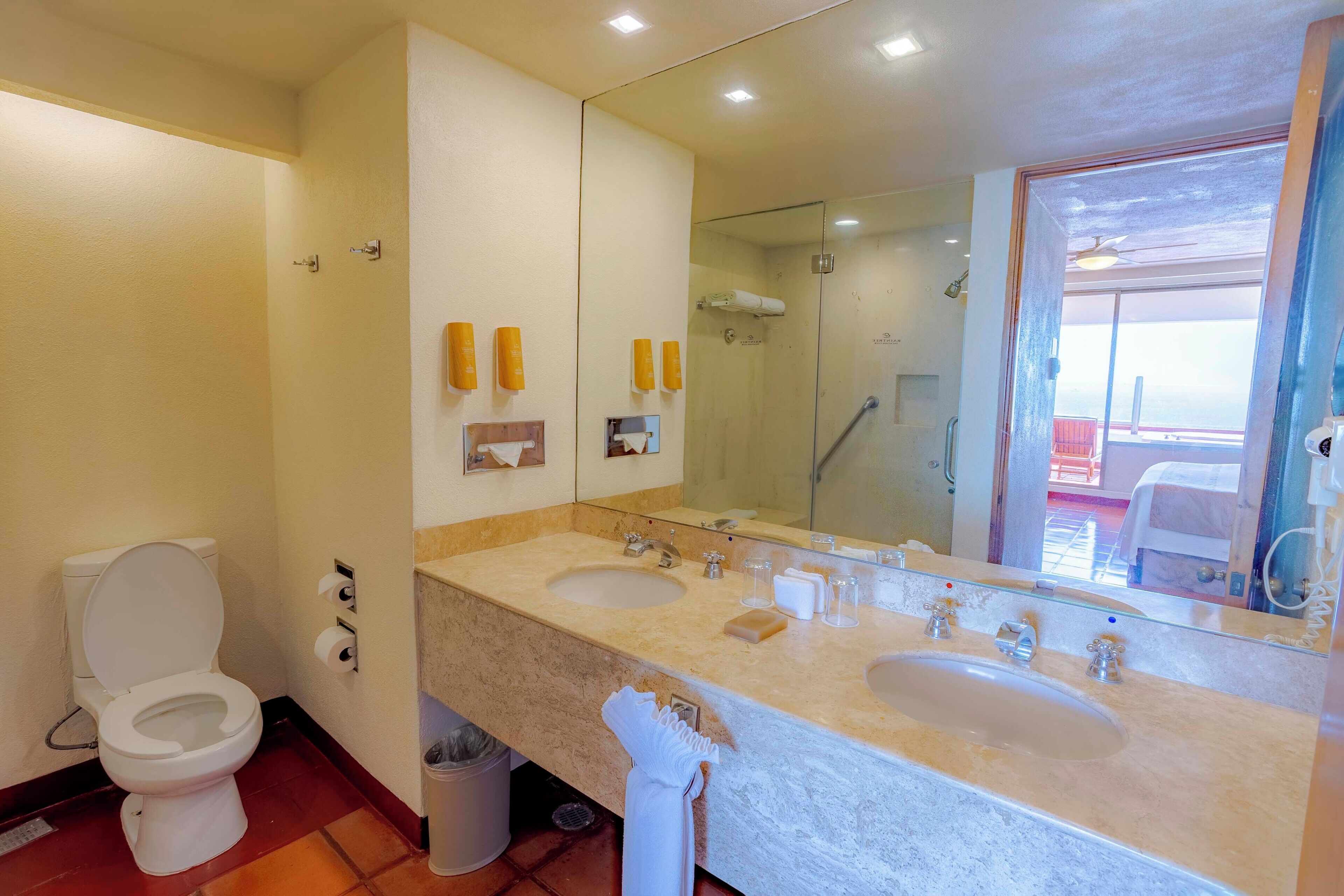 Ein Badezimmer mit zwei Waschbecken, einer Toilette, einer Dusche und einem großen Spiegel.
