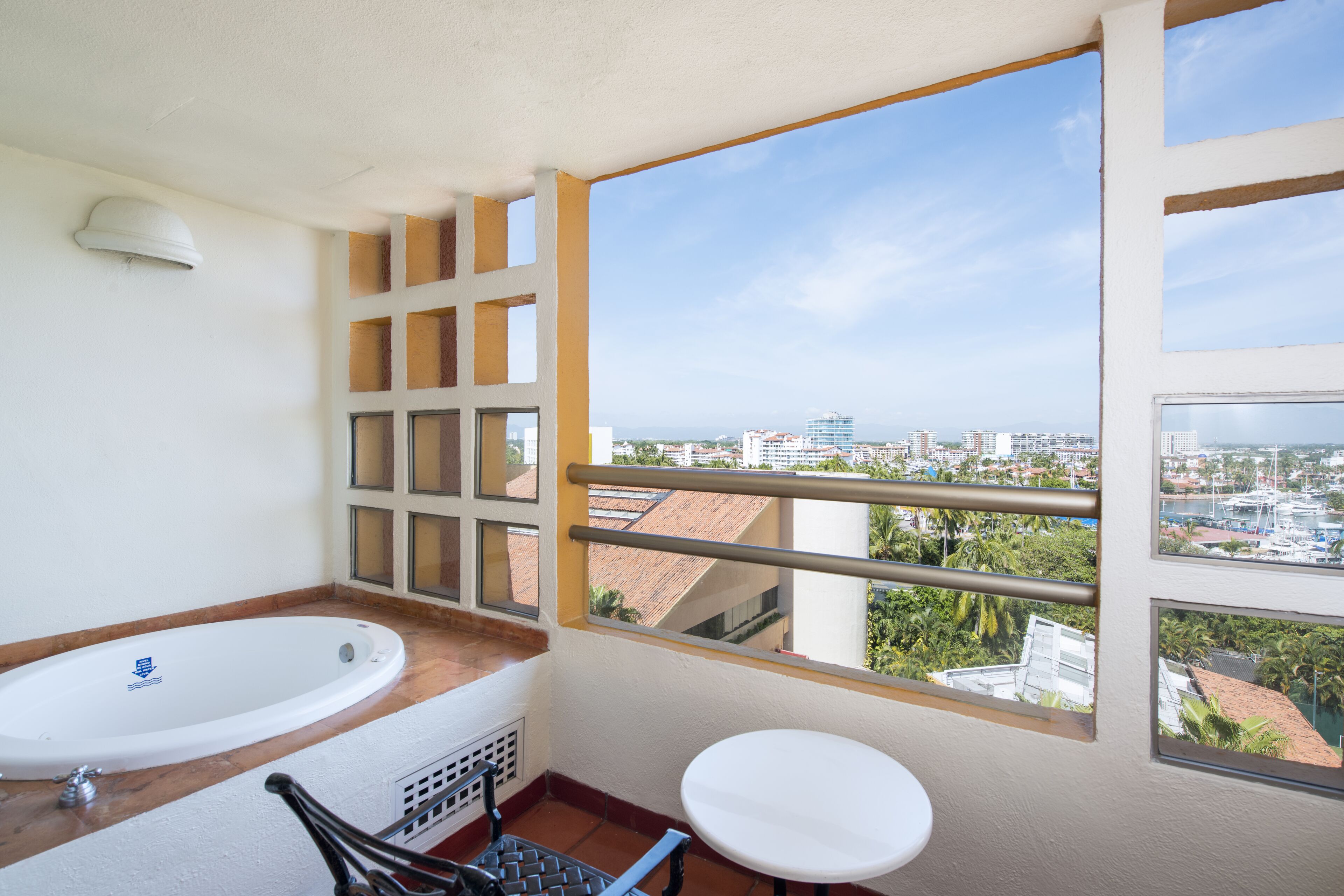 A bathroom with a bathtub, a toilet, and a window with a city view.