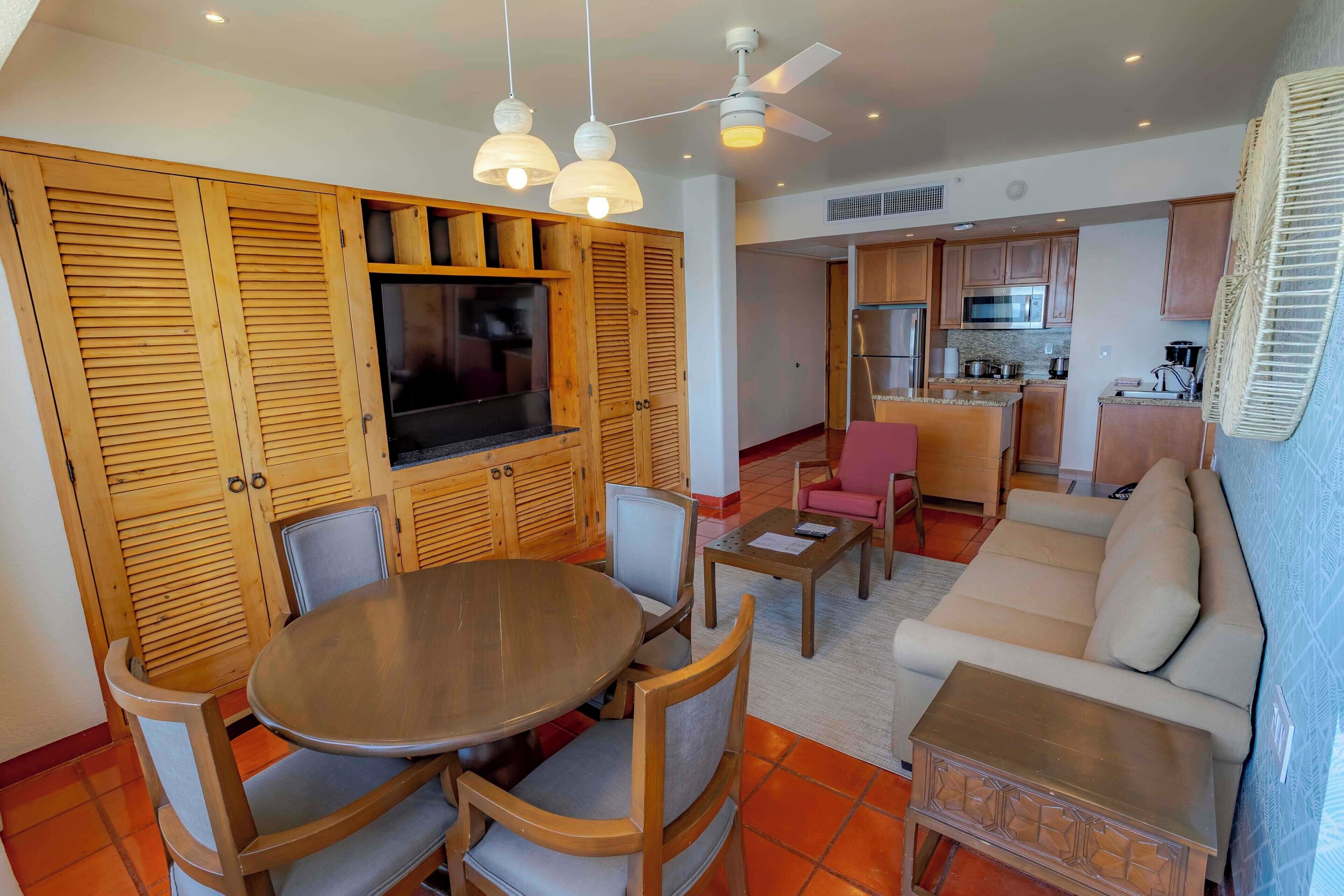 A compact living space with a dining area, a sofa, a kitchen, and a ceiling fan.