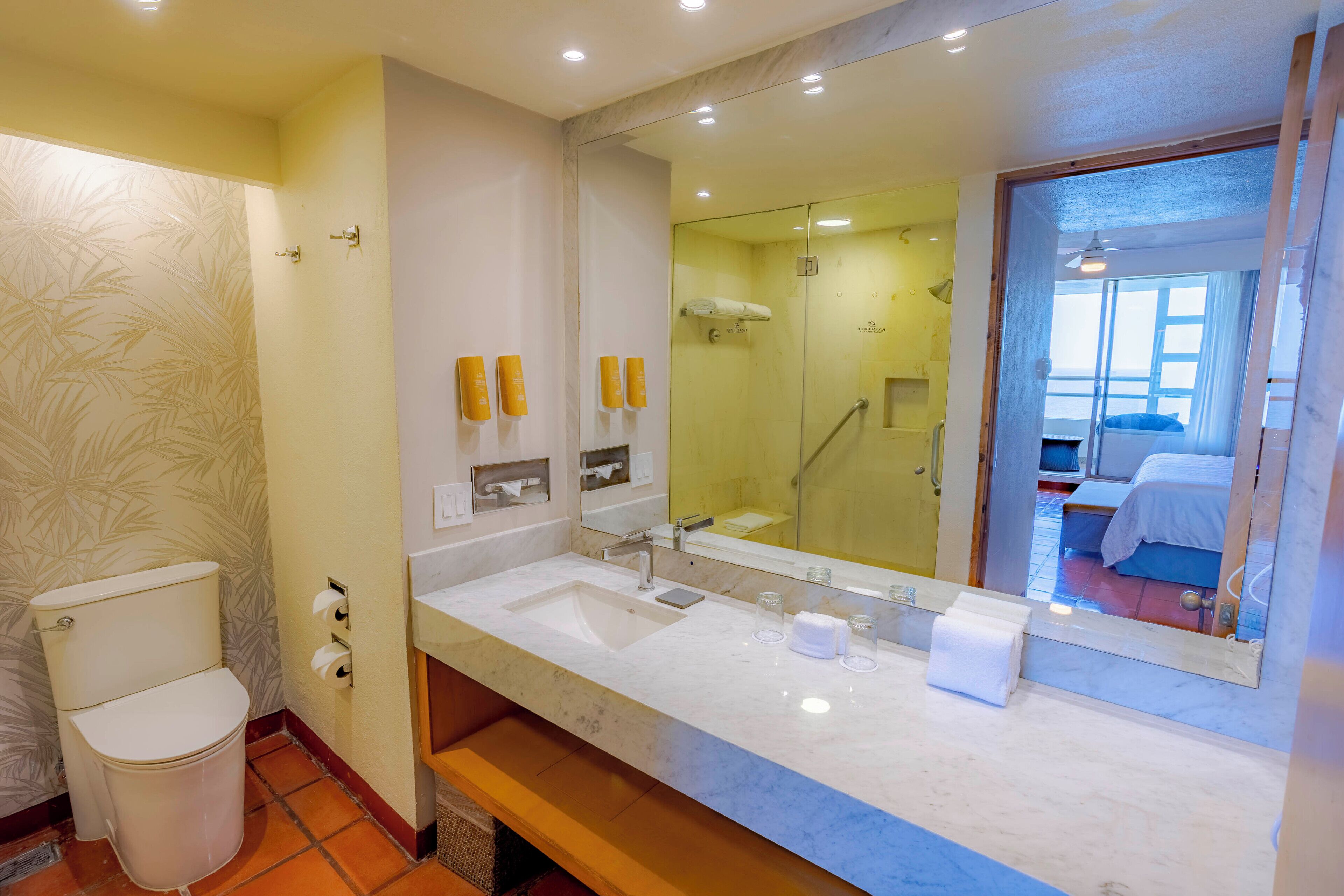Une salle de bain comprenant des toilettes, un lavabo, un miroir et un espace douche.