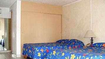 Una habitación con dos camas, una puerta, una lámpara y piso de baldosas.