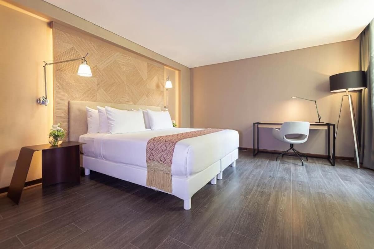 Een hotelkamer met een bed, nachtkastjes, een stoel en een lamp.