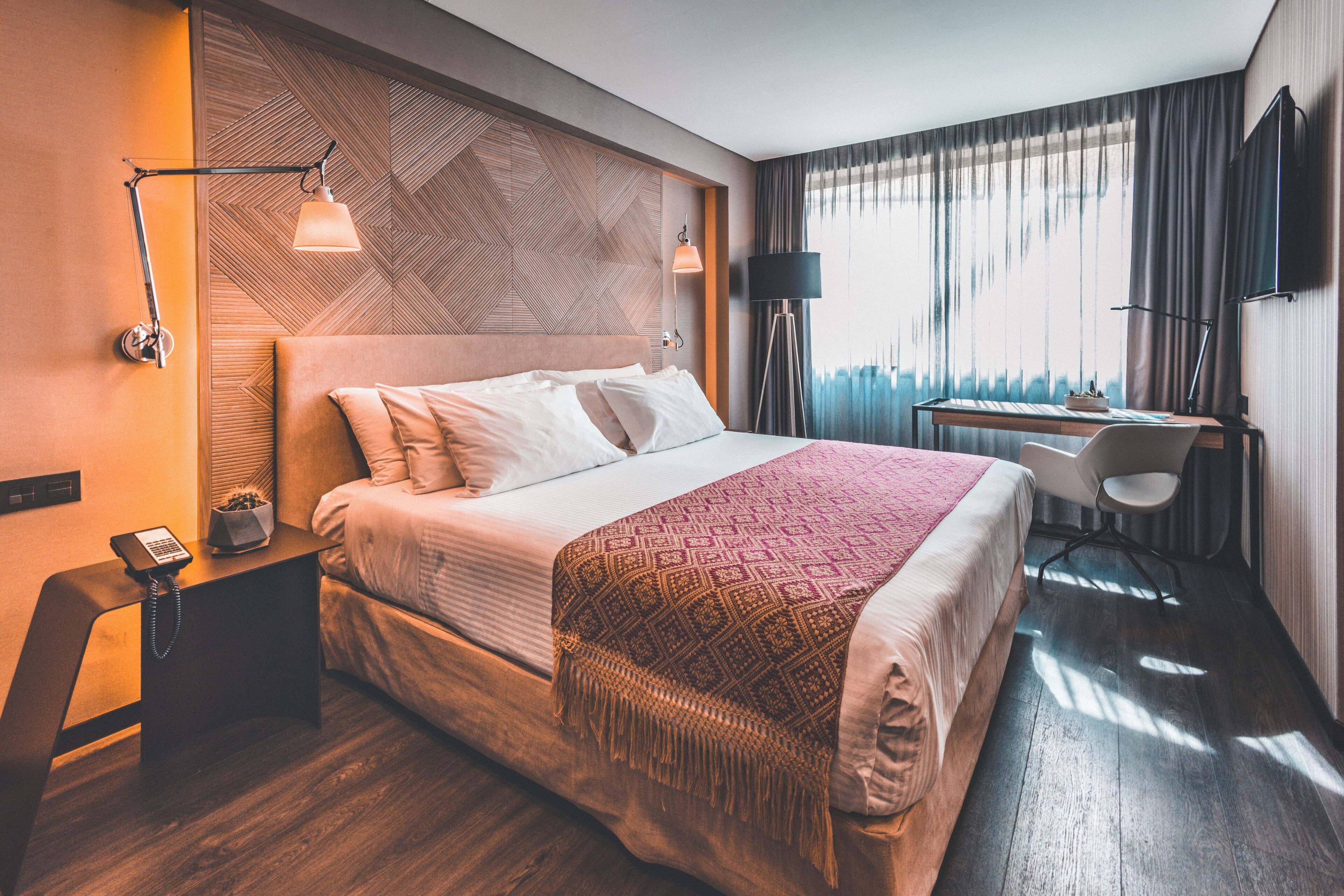 Une chambre d’hôtel équipée d’un lit, d’un bureau, d’une chaise et d’un téléviseur fixé au mur.