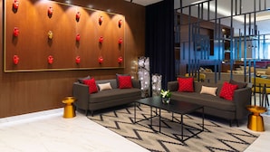 Un vestíbulo moderno con una gran pared de madera, dos sofás con cojines rojos, una mesita de centro y jarrones decorativos.
