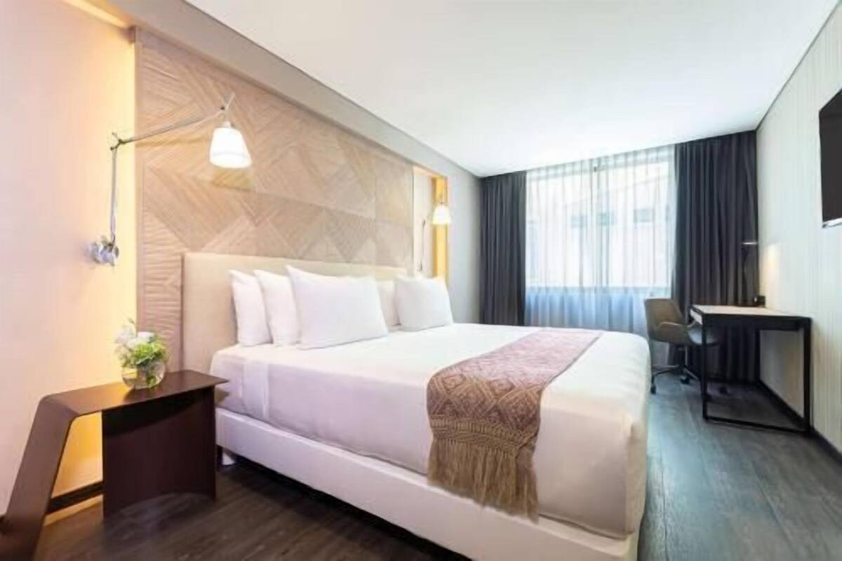 Een hotelkamer met een groot bed, nachtkastjes, een bureau en een televisie.
