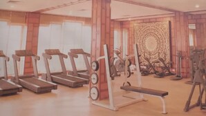 A gym with treadmills, weight machines, and a patterned wall. - Palms Hotel (Mumbai)