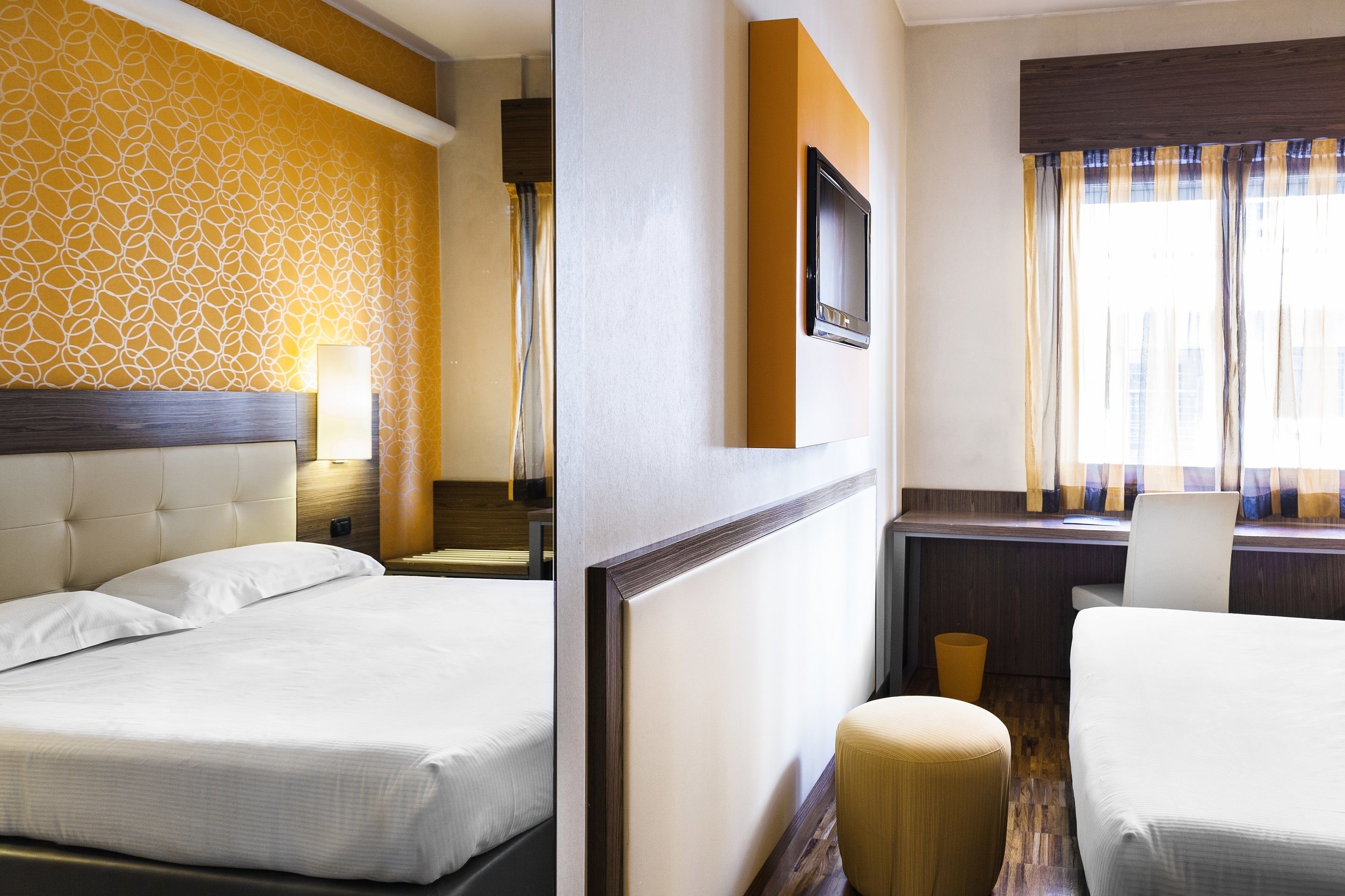 Habitación de hotel con dos camas, un escritorio, una silla y un televisor.
