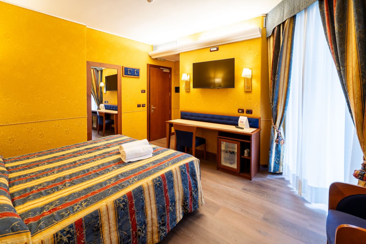 A hotel room with a large bed, a desk, and a television.
