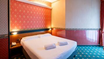 Ein Hotelzimmer mit Bett, Nachttisch, Telefon und einem Fenster mit Vorhängen.