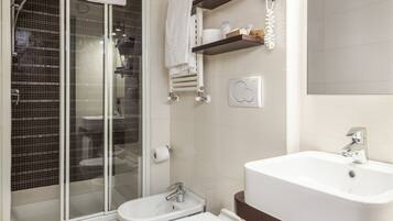 Un bagno moderno con doccia vetrata, un bidet, un lavandino e un WC.