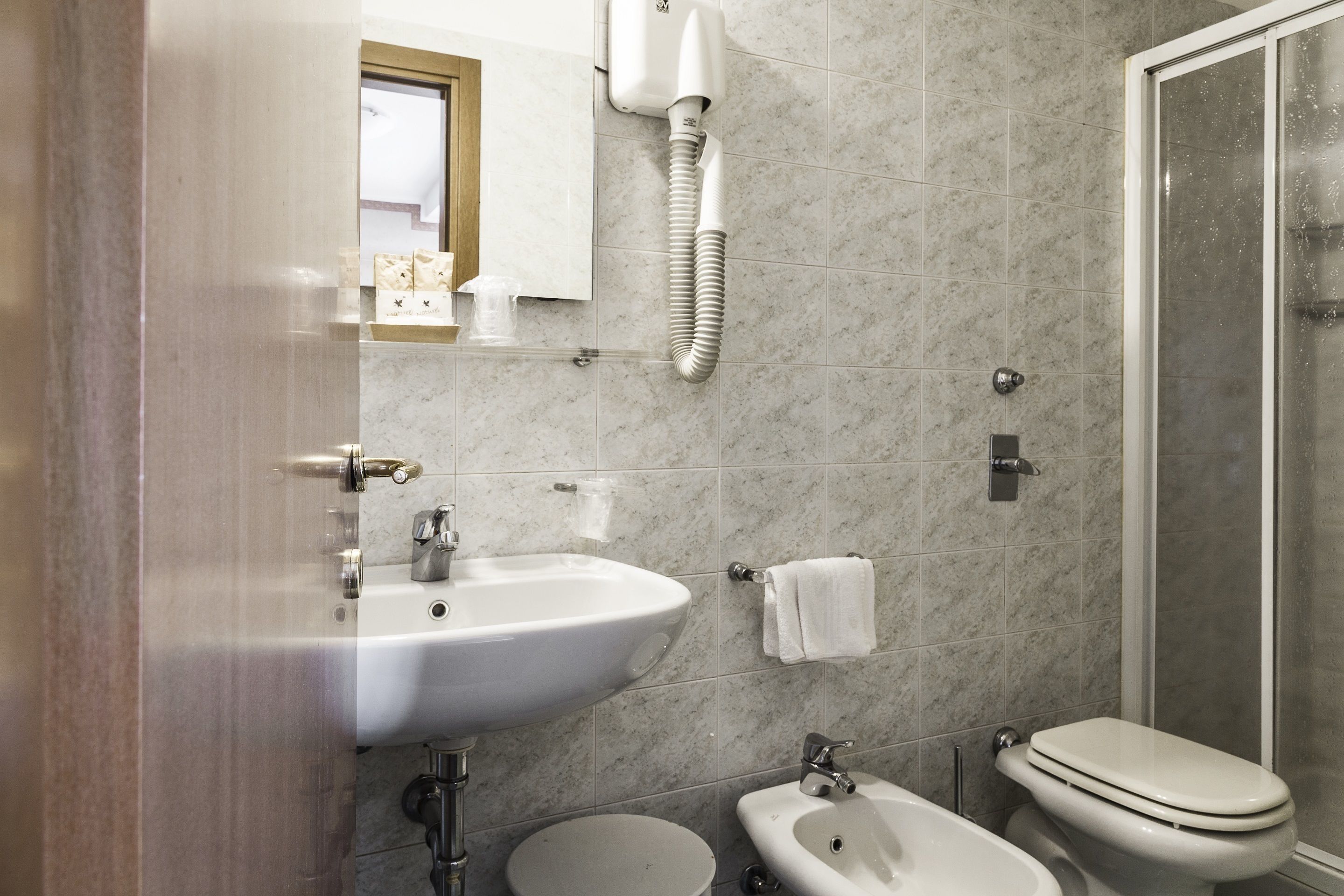 A bathroom with a sink, toilet, bidet, and a shower area.