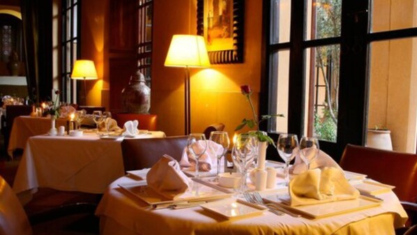 Un restaurante con mesas dispuestas para comer, con iluminación cálida y amplios ventanales.