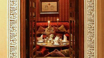 Un pasillo estrecho con puertas y paredes de madera ornamentada, que conduce a un área de estar con una mesa dispuesta para comer.