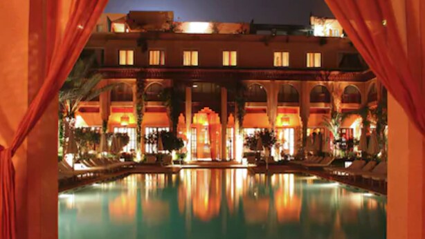 Un hotel con piscina, varios balcones y un patio con zonas de estar.