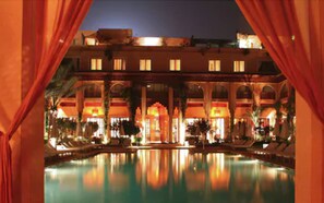 Un hotel con piscina, varios balcones y un patio con zonas de estar.