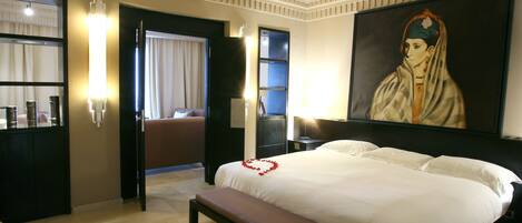 Ein Hotelzimmer mit einem großen Bett, einer Bank, einem Gemälde an der Wand und einem durchgegangenen Tür erkennbaren Badezimmer.
