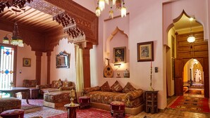 Un intérieur traditionnel agrémenté de meubles en bois richement décorés, de tapis à motifs et d’un espace salon central.