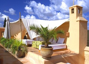 A tented outdoor area with a bed, potted plants, and a small tower structure. - Riyad El Cadi (Marrakech)
