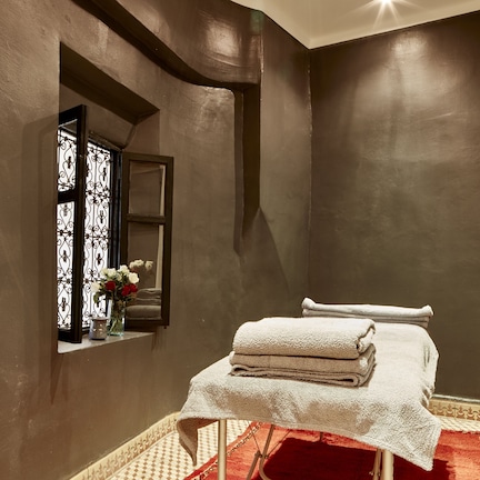 A room with a bed, a window with a decorative iron grill, a mirror, and a red carpet.