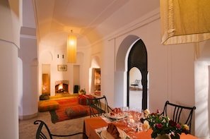 A dining area with a fireplace, a table set for two, and a view of the courtyard.