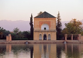 Un edificio con un arco central, un balcón y su reflejo en el agua.