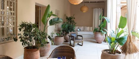 A dining area with wicker furniture, potted plants, and a buffet tray.