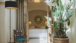 A bedroom with a bed, a chair, a floor lamp, and a large potted plant. - Les Deux Tours (Marrakech)