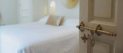 Un dormitorio con cama, una puerta de pomo de latón y un espejo redondo en la pared.